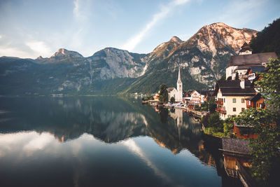 Scenic view of lake by buildings and mountains against sky