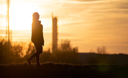 Silhouette man standing on field against sky during sunset