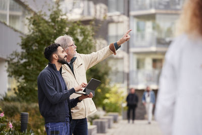 Two men with laptop in courtyard