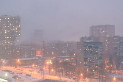 Illuminated buildings in city during rainy season