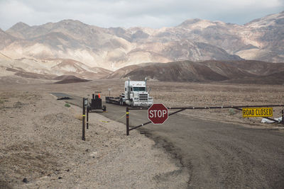 Road sign by mountains against sky