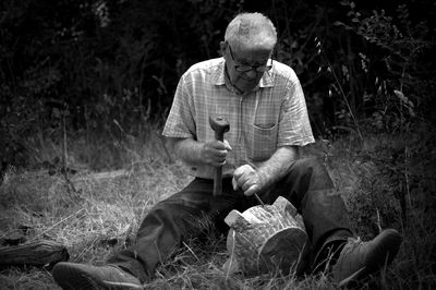 Senior man carving with chisel and hammer