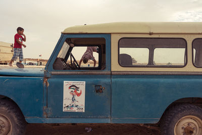 People standing by car against sky