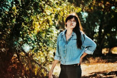 Young woman looking away while standing in forest