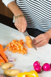 Woman slicing vegetables while cooking stew. close up of woman hands cutting vegetables