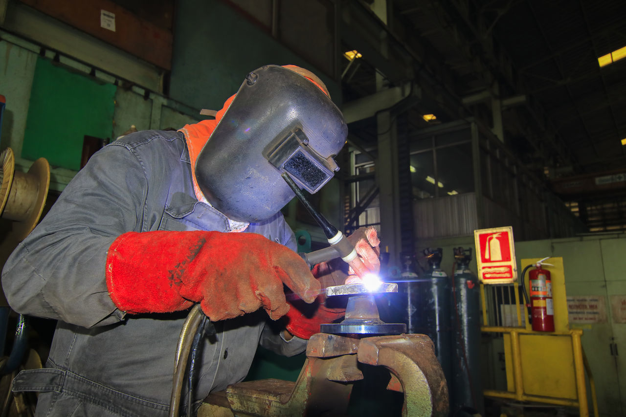 MAN WORKING ON METAL GRATE IN ILLUMINATED ROOM