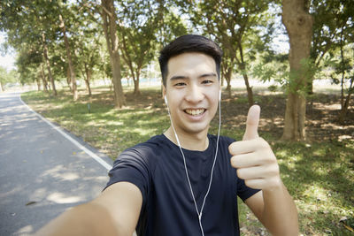 Portrait of smiling young man standing against trees