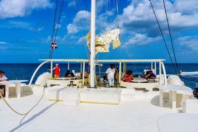 Group of people on sailboat at sea against sky