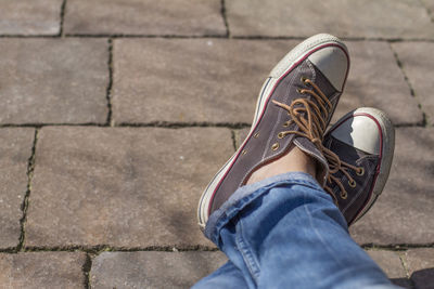 Low section of man wearing canvas shoes on footpath