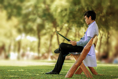 Side view of man sitting on seat in field