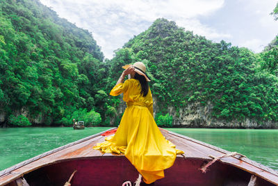 Rear view of woman on boat against trees