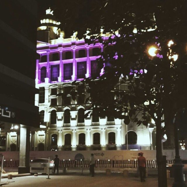 architecture, building exterior, built structure, illuminated, night, city, street light, incidental people, low angle view, tree, building, travel destinations, lighting equipment, street, famous place, facade, arch, outdoors, city life, sky