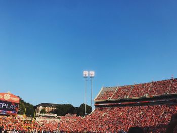 Crowd in front of built structure against clear blue sky