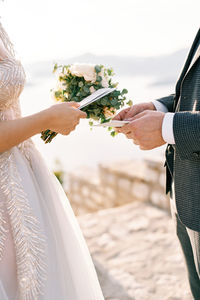 Midsection of bride holding bouquet