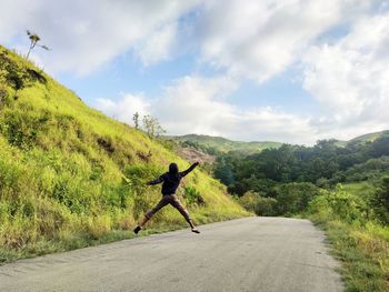 Rear view of man riding bicycle on road against sky