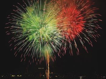 Low angle view of firework display over city at night