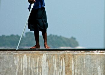 Low section of worker cleaning infinity pool against sky