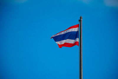 Low angle view of flags flag against blue sky