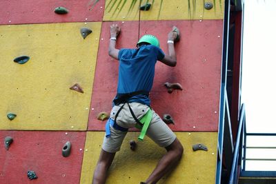 Low angle view of teenage boy climbing wall