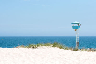 Lifeguard hut on beach against clear blue sky