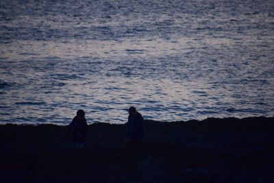 Rear view of silhouette couple walking on beach