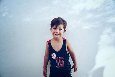 Smiling boy standing against white wall