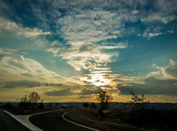 Road passing through landscape against cloudy sky