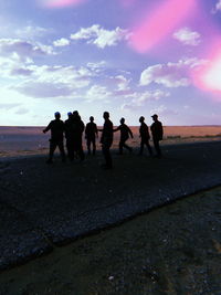 Silhouette people standing on land against sky during sunset