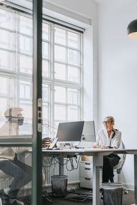 Male and female business people discussing while sitting at desk in office