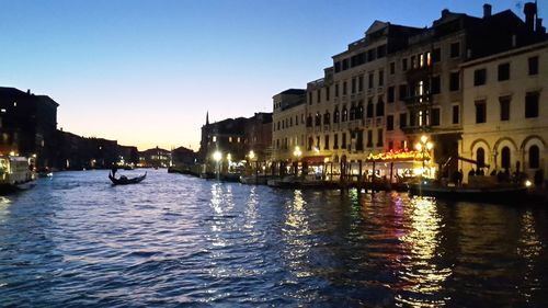 Canal amidst buildings in city at dusk