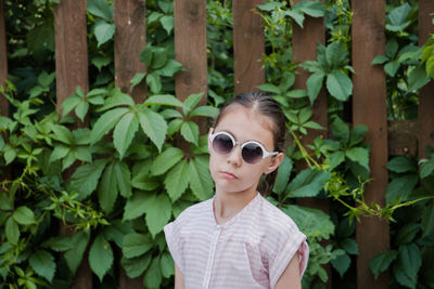 Portrait of girl wearing sunglasses standing against plants