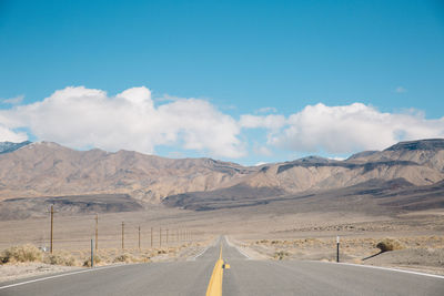 Empty road by mountains against sky