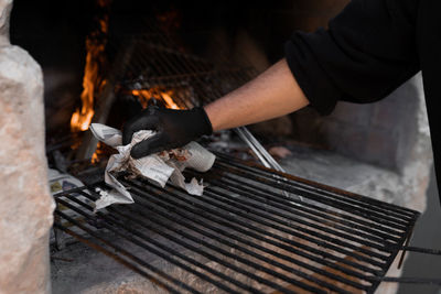 Unrecognizable man cleaning the grill for the barbecue, concept of lunch party outdoors.