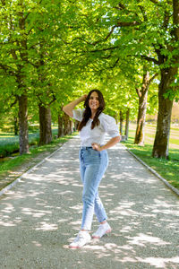 Portrait of beautiful young woman standing on path in park during spring.