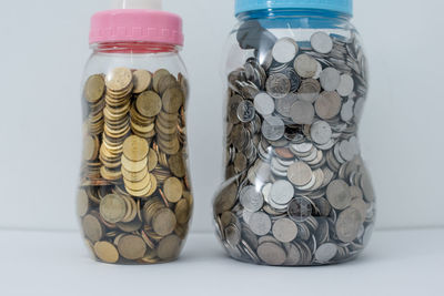 Close-up of coins in glass jar on white background