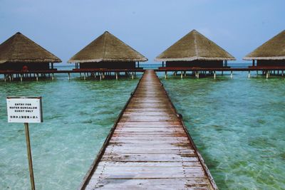 Pier over sea and houses against sky