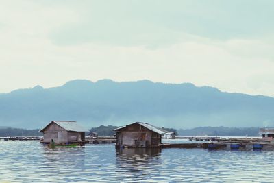 Houses by lake and buildings against sky