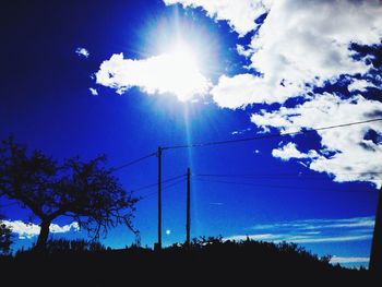 Low angle view of sun shining through clouds