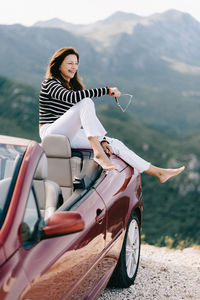 Woman sitting on motorcycle against mountains