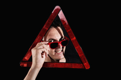 Portrait of young woman wearing sunglasses against black background