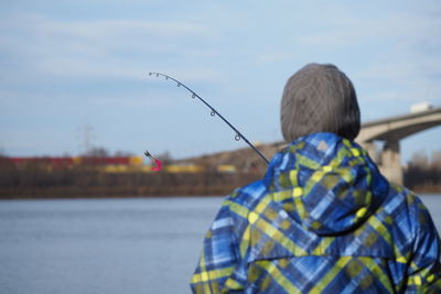 Rear view of man standing by lake