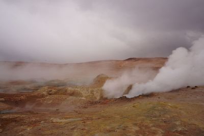 Smoke emitting from volcanic landscape against sky