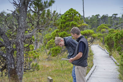 Side view of men standing on boardwalk in forest