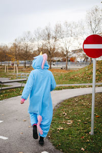 Rear view of woman wearing costume walking on footpath