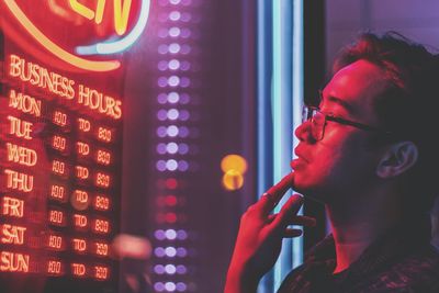 Side view of young man looking at illuminated information sign