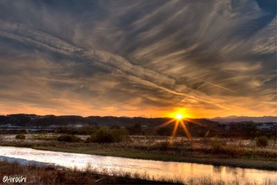 Scenic view of field against dramatic sky during sunset