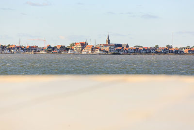 Sea by buildings against sky in city