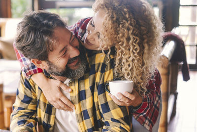 Cheerful couple embracing while sitting at home