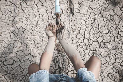 Midsection of women on arid land by faucet