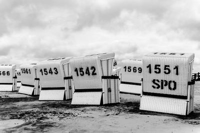 Text on hooded beach chairs against sky